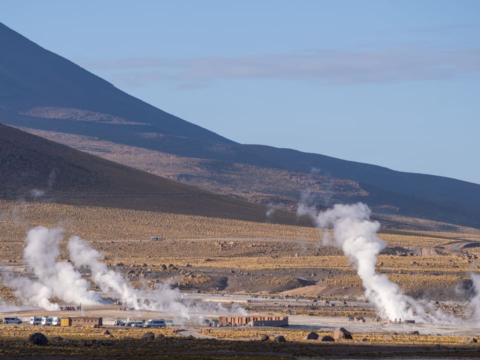 Fumarolas do campo geotérmico El Tatio ao amanhecer, com montanhas ao fundo
