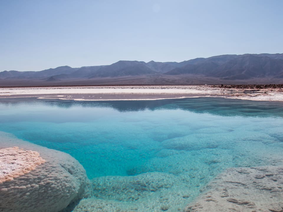 Lagoa azul-turquesa cercada por crostas de sal nas Lagunas Escondidas de Baltinache