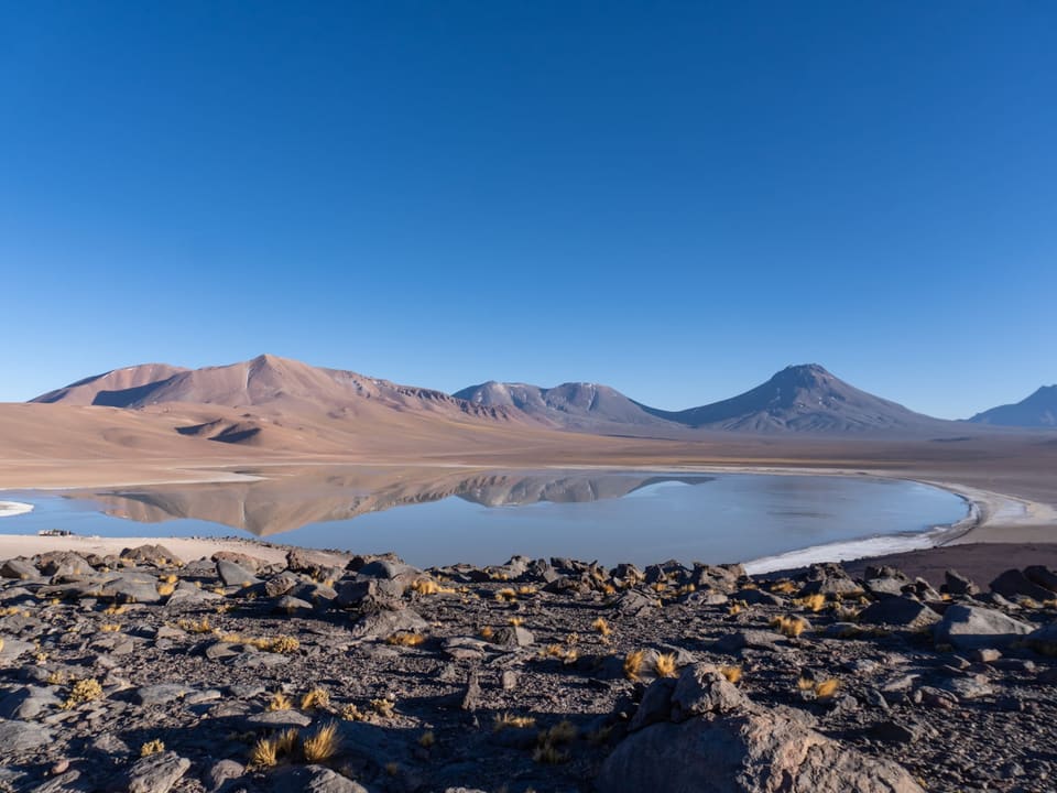 Laguna altiplânica azul cercada por montanhas andinas