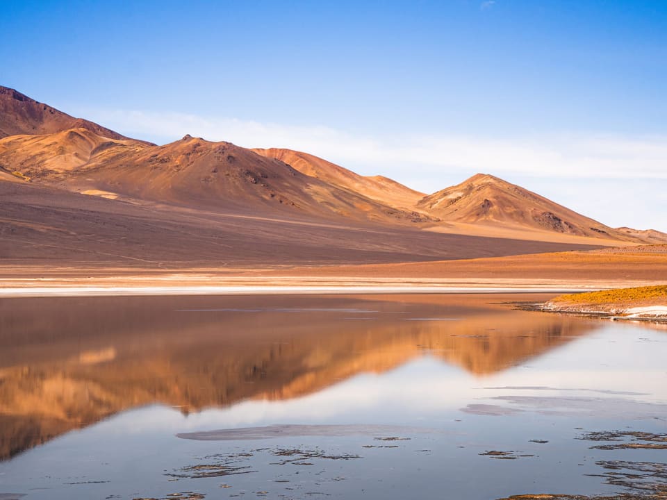 Montanhas refletidas em um salar de águas calmas