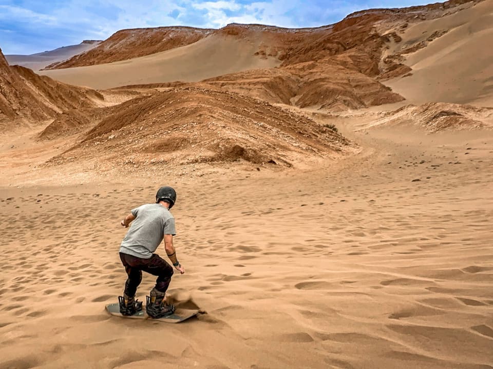 Praticante descendo uma duna de prancha
