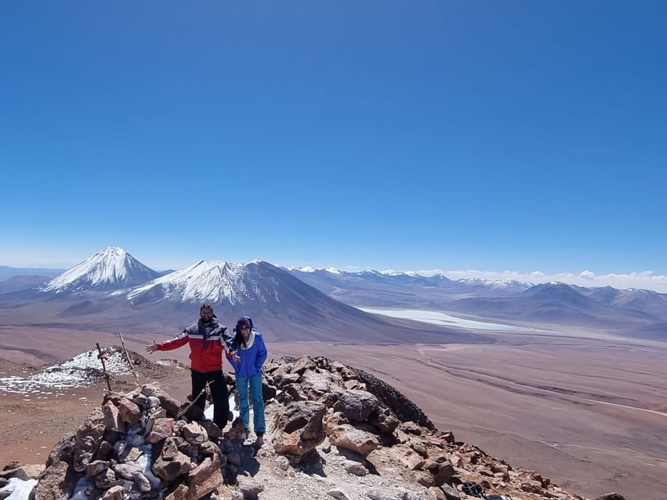 Trekkers no cume do Cerro Toco com vulcões nevados ao fundo