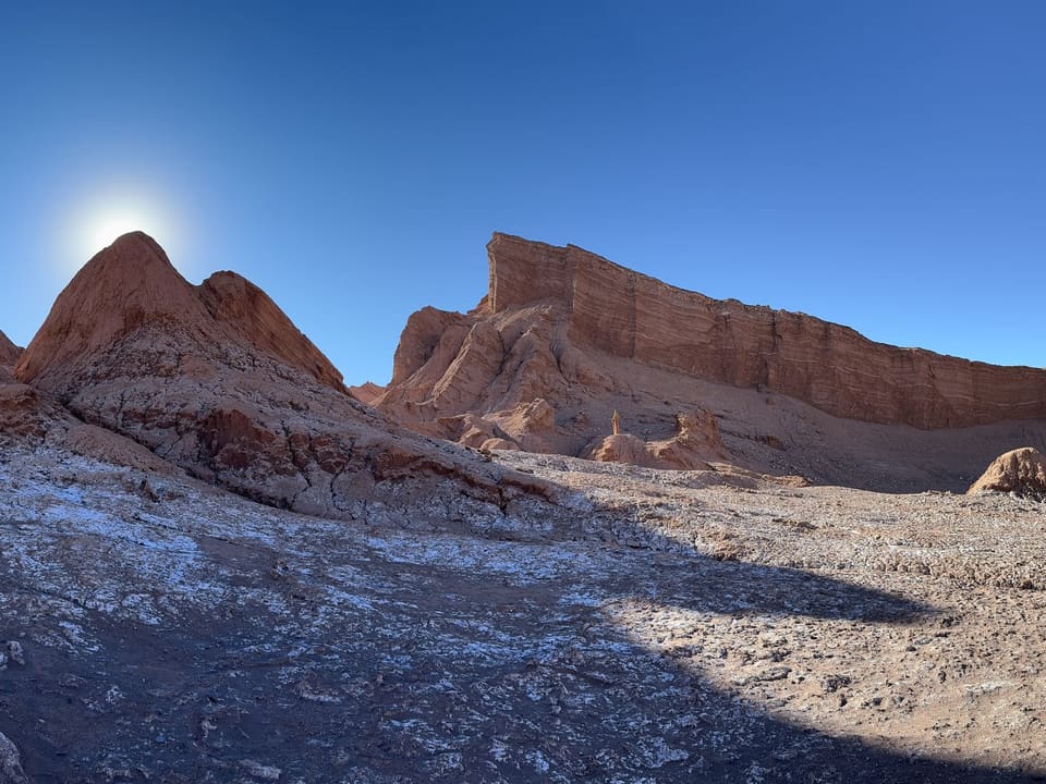 Formações rochosas do Valle de la Luna sob céu azul, com o sol ao fundo