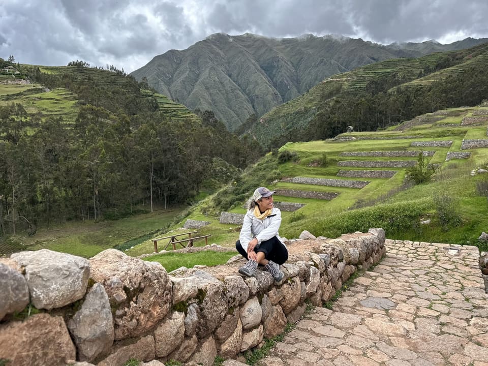 Viajante sentada em muro de pedra diante do vale de Chinchero