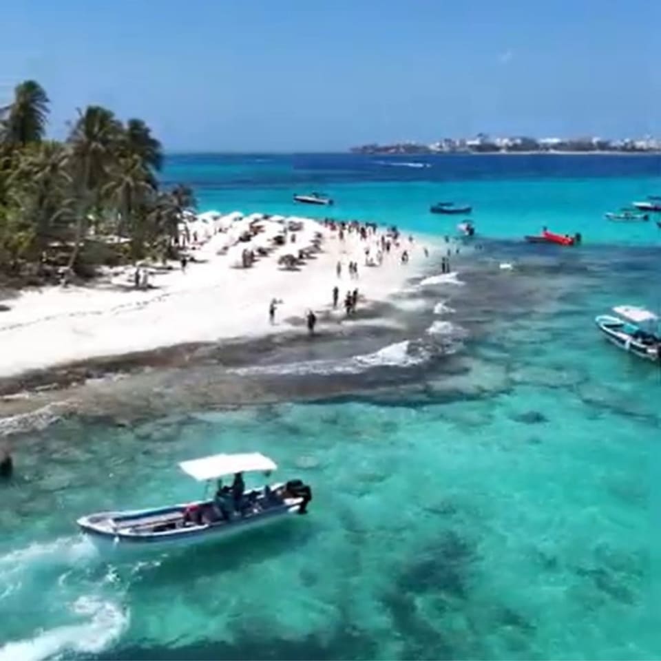 Lancha chegando à praia de areia branca de Johnny Cay