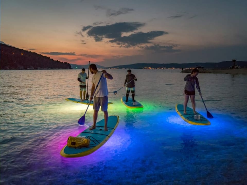 Pranchas iluminadas de stand up paddle ao entardecer