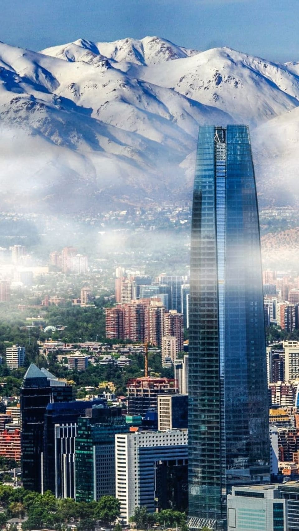 Arranha-céu Gran Torre Santiago e prédios da cidade diante da Cordilheira dos Andes nevada