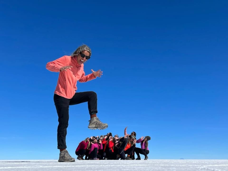 Viajante saltando no salar com o grupo ao fundo