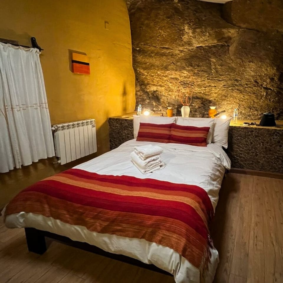 Quarto de hotel com parede de pedra e cama de casal